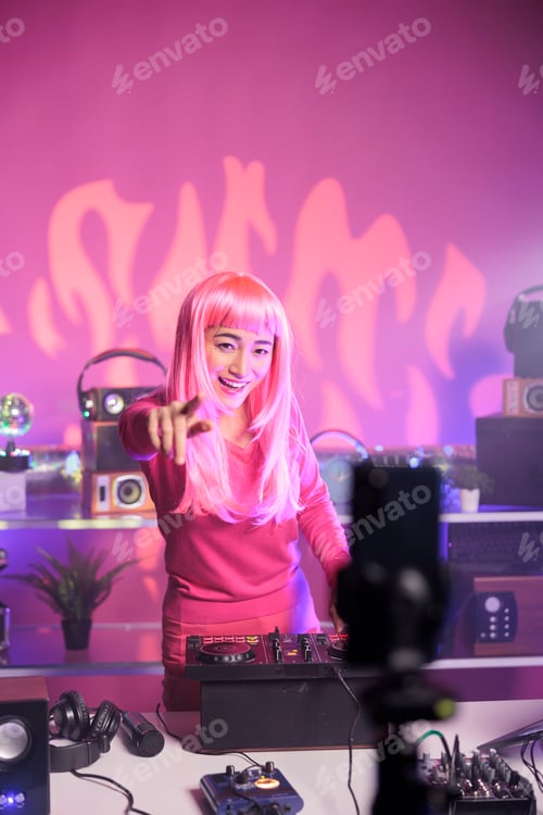 Preview: Woman with pink hair playing techno song at professional turntables while filimg process with mobile