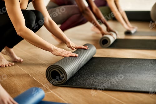 Preview: Close-up of athletic women rolling their exercise mats after sports training in a gym.