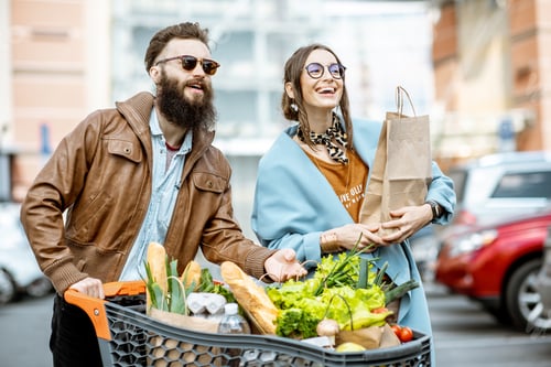 Preview: Man and woman with shopping cart full of food outdooors