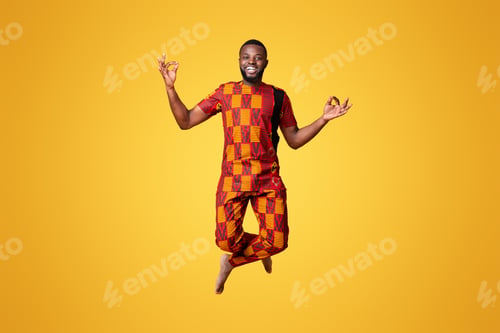 Preview: Carefree african guy jumping up over yellow studio background