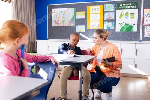 Preview: Helping african american boy with tablet in school, female teacher and another student watching