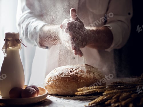 Preview: A man sprinkles flour over fresh homemade bread.