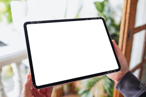 Preview: a woman holding and using digital tablet with blank white desktop screen on balcony at home