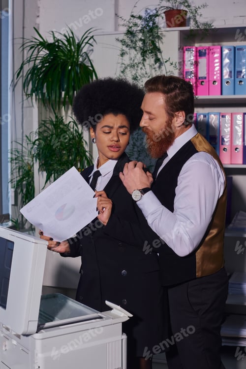 Preview: displeased african american woman feeling discomfort near bearded businessman seducing her in office
