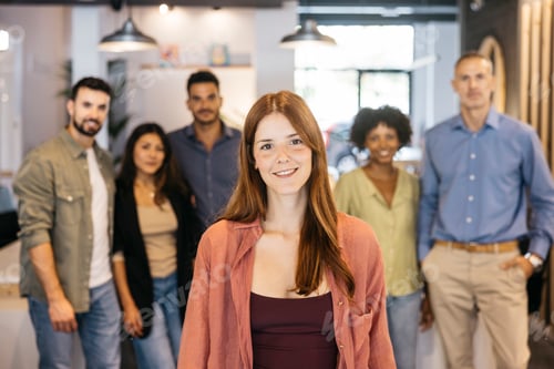 Preview: Young woman smiling with diverse business team behind her