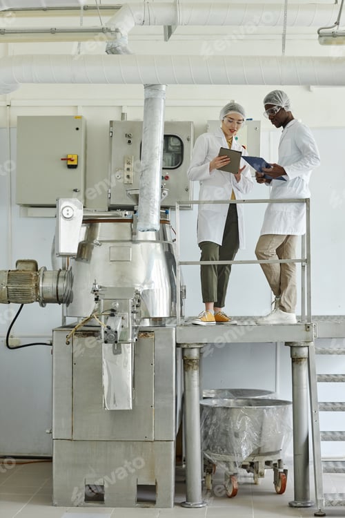 Preview: Of two workers wearing lab coats using laptop in clean factory workshop