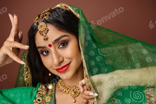 Preview: attractive jolly indian woman with bindi dot and green veil gesturing and looking at camera