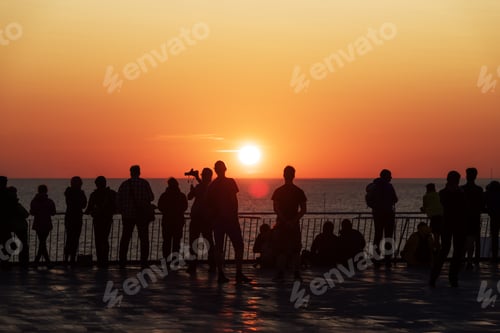 Preview: Silhouettes of people against the setting sun on deck of a cruise ship