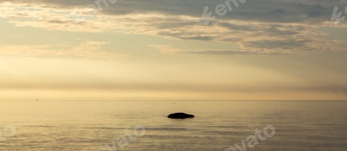 Preview: Golden sunrise over a calm sea and some clouds in a blue sky