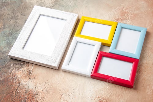 Preview: Side view of small and big colorful picture frames hanging on nude color wall with free space