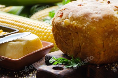 Preview: Zoomed view at homemade loaf of cornbread on wooden kitchen table. Cobs and butter aside