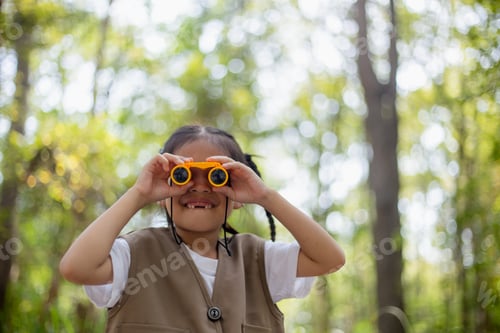 Preview: Happy Little Asian girls looking ahead and smiling child with the binoculars in the park.
