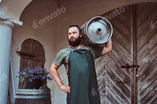 Preview: Brewer in apron holds barrel with craft beer at brewery factory.