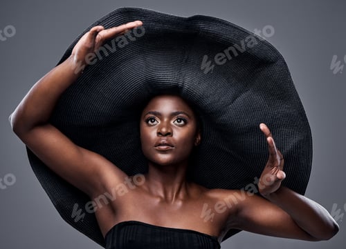 Preview: Shot of a young woman wearing a oversized sunhat against a grey background