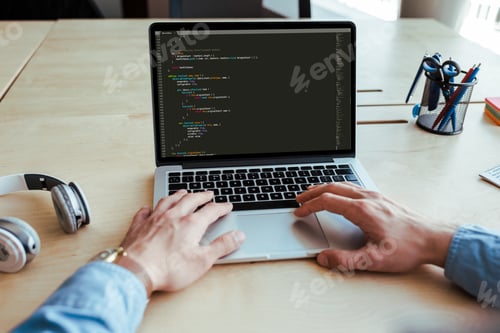 Preview: Partial view of male hands with laptop near headphones at table in coworking space