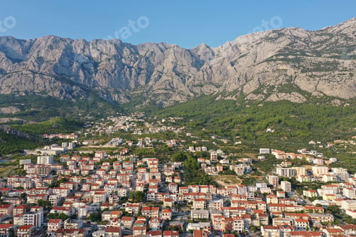 Preview: Aerial shot of buildings near the mountains under a clear blue sky at daytime in Makarska, Croatia