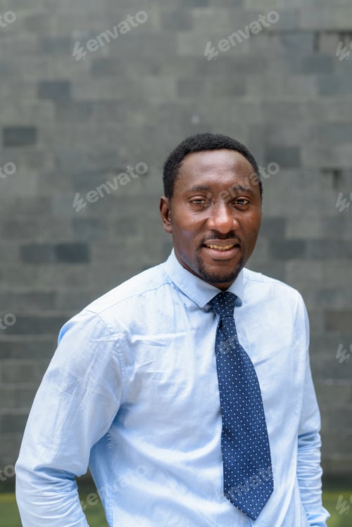Preview: Vertical portrait of handsome African businessman in city smiling