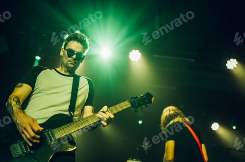 Preview: Guitarist performing live on stage under green lights