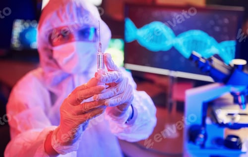 Preview: Nurse in mask and white uniform, holding syringe and sitting in neon lighted laboratory