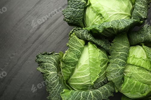 Preview: Fresh Savoy cabbages on black textured table, flat lay. Space for text
