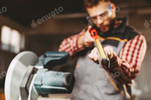 Preview: Young man work in home workshop measures a metal pipe