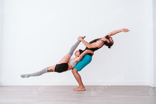 Preview: young couple Couple practicing acro yoga in white studio or gym. Healthy lifestyle