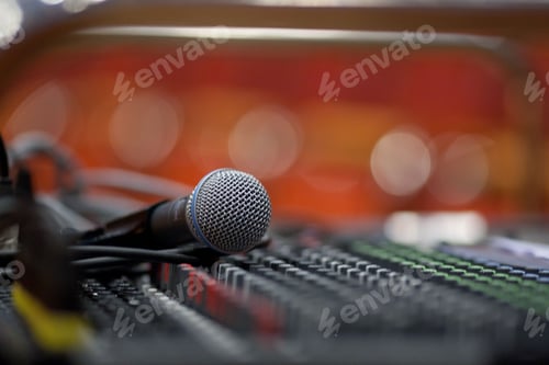 Preview: Closeup shot of a microphone lying on sound equipment against bokeh background
