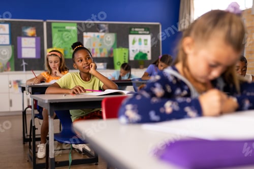 Preview: African american schoolgirl thinking while studying with children in classroom