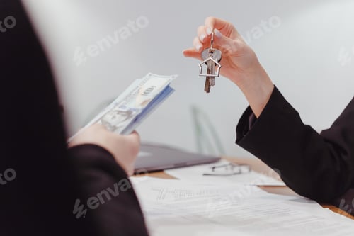 Preview: Young woman realtor holds out the keys to the real estate, the client give money