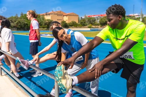 Preview: Athletes stretching legs on track and field, preparing for competition