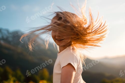 Preview: Happy little girl on the background of sunset and mountains. Hair in the wind