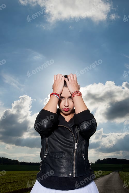 Preview: Portrait of young woman on rural road with head in hands