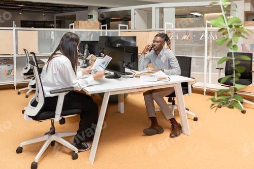 Preview: two multiethnic business people working together at the table in the coworking office