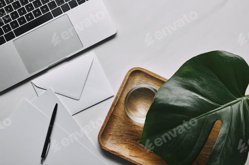 Preview: Flat lay template with envelope and laptop on white marble background