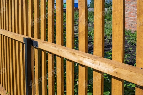 Preview: Close-up of a new wooden picket fence in the backyard of a country house, a sunny summer day