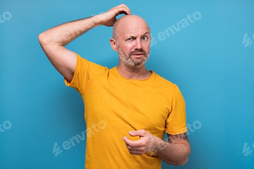 Preview: Mature man having doubts and with confuse face expression while scratching head