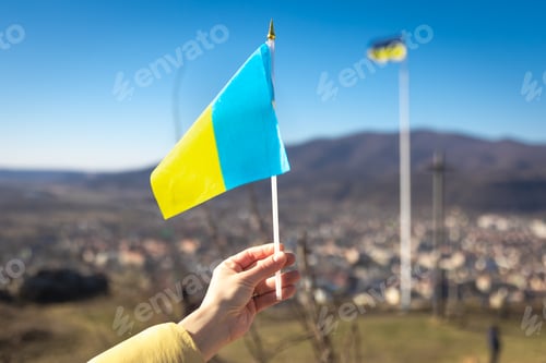 Preview: Flag of Ukraine in female hands against the sky.