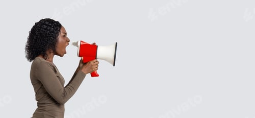 Preview: Young black woman shouting in megaphone over grey background