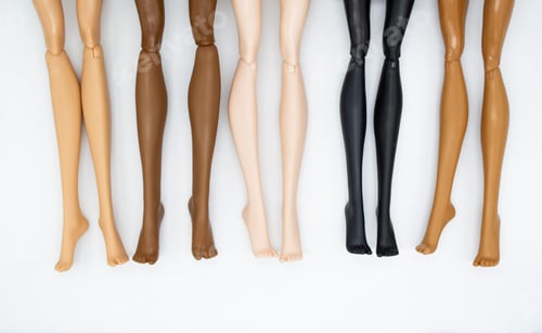 Preview: Legs of dolls representing different races on a white background. friendship, health, beauty.