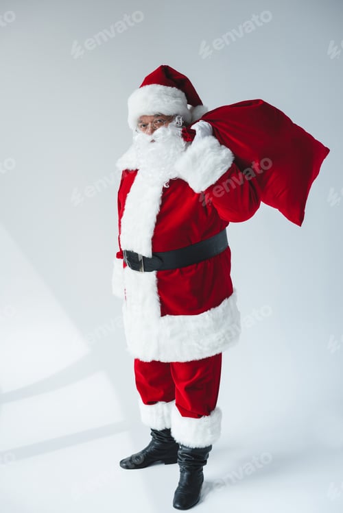 Preview: santa claus holding bag full of presents and looking at camera isolated on white