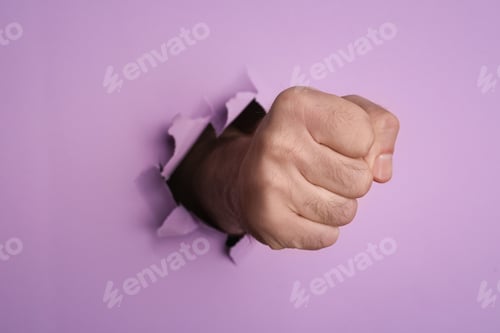 Preview: Man breaking through violet paper with fist, closeup