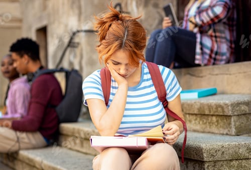 Preview: Female student sits on the stairs studing.