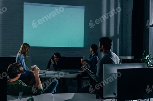 Preview: people watching presentation in office at nighttime. blank screen