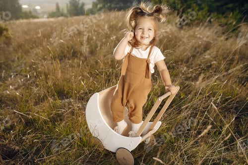 Preview: Cute little girl playing in a park with white carriage