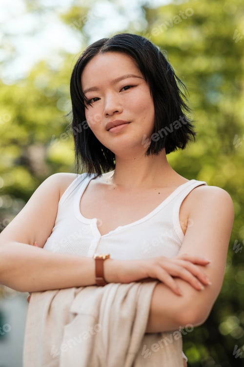 Preview: Young asian woman posing with crossed arms in park