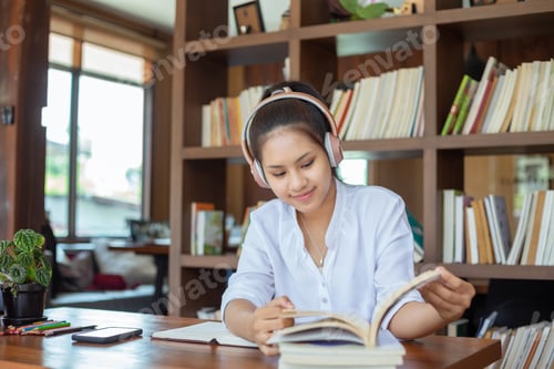 Preview: Female student to read and work with listening teaching book online in the university library.