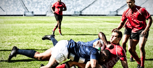 Preview: Digital composite image of team of rugby players tackling each other to win the ball in stadium