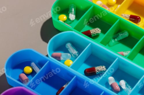 Preview: Bright multi-colored pill boxes with medicines on a gray background