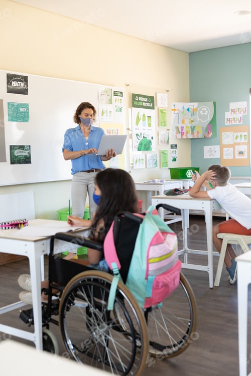 Preview: Female teacher wearing face mask using laptop to teach students in class