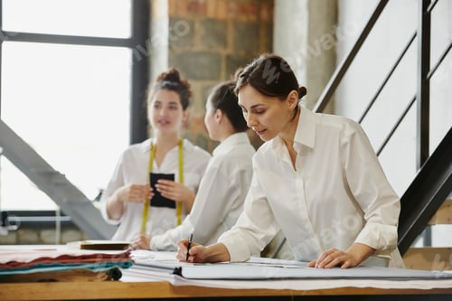 Preview: Two young female designers of clothes phoning clients about orders in workshop
